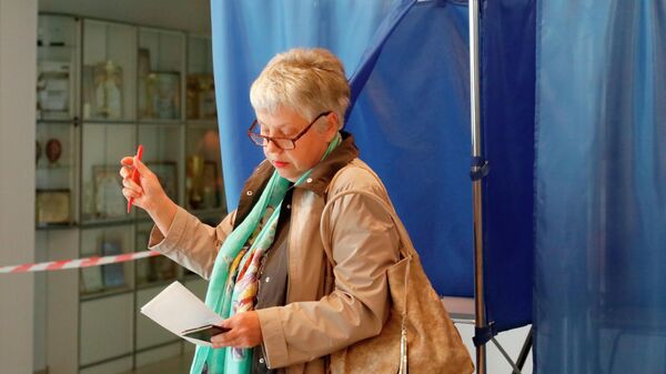 Женщина голосует на референдуме на избирательном участке в поселке Дубовое Белгородского района