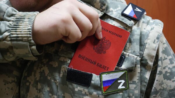 Мужчина, призванный на воинскую службу в ходе частичной мобилизации, кладет в карман военный билет в комиссариате Краснодара