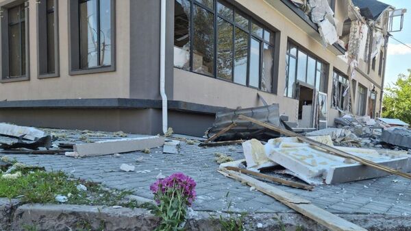 Цветы у разрушенного в результате обстрела ВСУ здания гостиницы Play в Херсоне