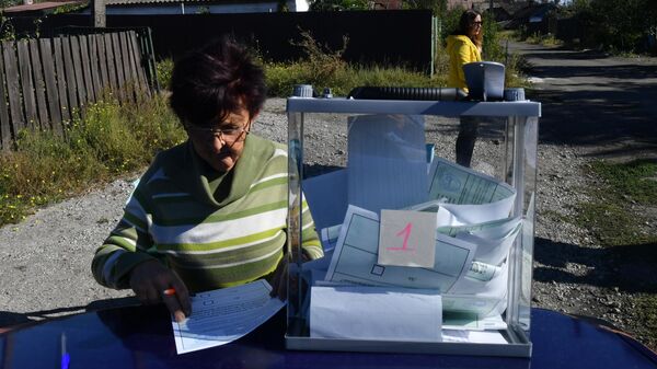 Женщина голосует на выездном избирательном участке
