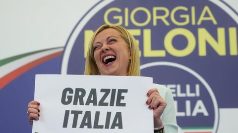 Лидер правой партии Братья Италии Джорджия Мелони держит плакат с надписью Спасибо, Италия в избирательном штабе своей партии в Риме