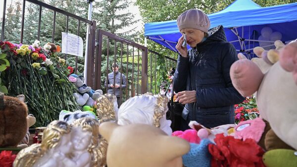 Женщина у стихийного мемориала у школы №88 в Ижевске