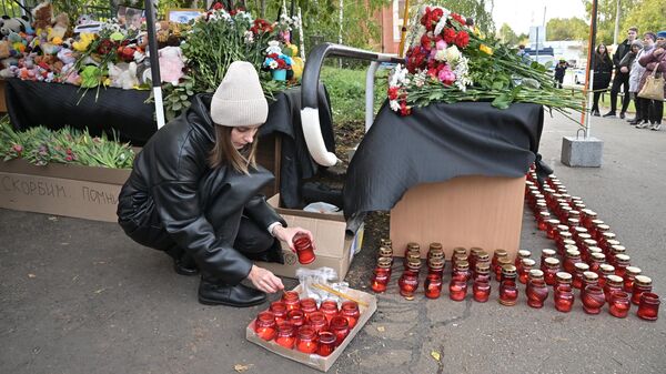 Девушка зажигает свечи у школы №88 в Ижевске