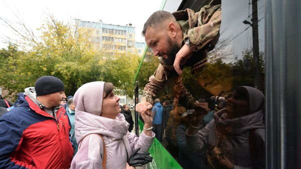 Родственники общаются у сборного пункта перед отправкой мужчин, призванных на военную службу в ходе частичной мобилизации, для проведения курса подготовки и боевого слаживания