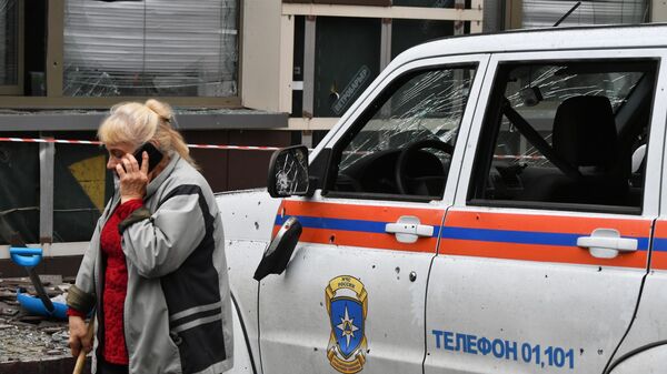 Женщина возле машины МЧС, поврежденной в результате обстрела со стороны ВСУ в Донецке