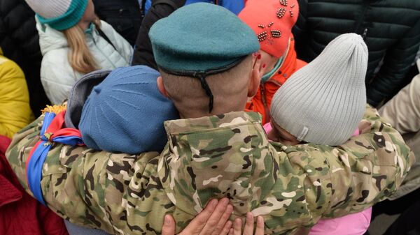 Мужчина, призванный на военную службу в ходе частичной мобилизации, прощается с родными у сборного пункта