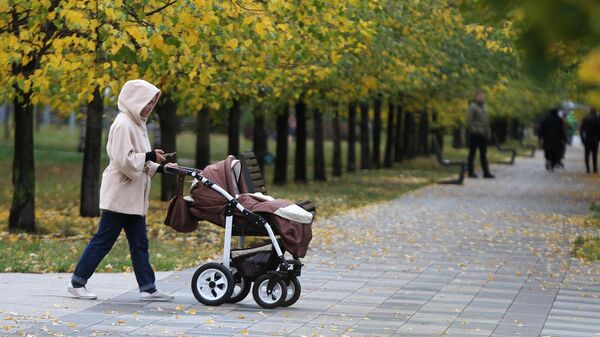 Женщина с коляской гуляет в Дюссельдорфском парке в Москве