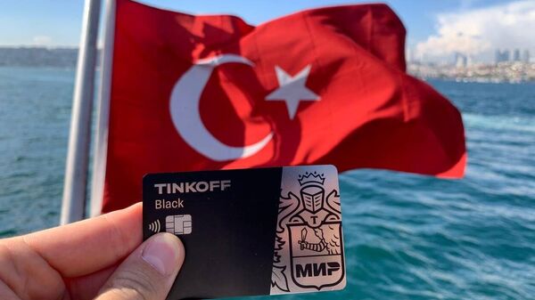 Карта Мир банка Тинькофф на фоне флага Турции в Стамбуле