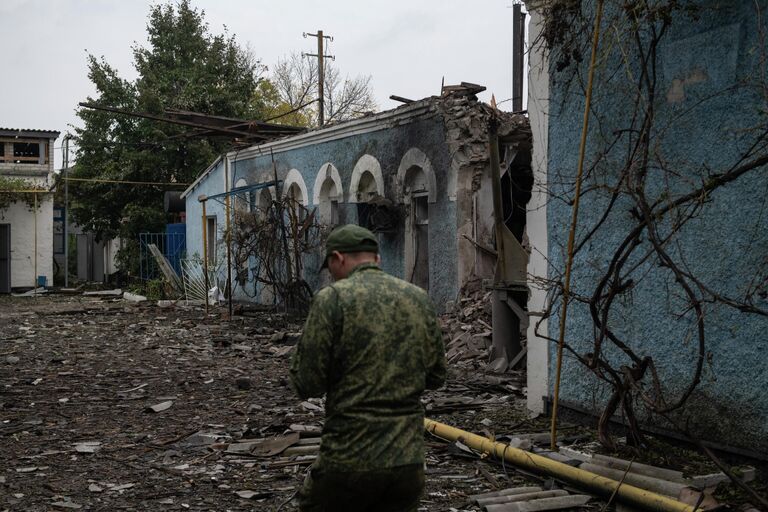 Мужчина на фоне разрушенного здания после обстрела со стороны ВСУ в городе Брянки в ЛНР