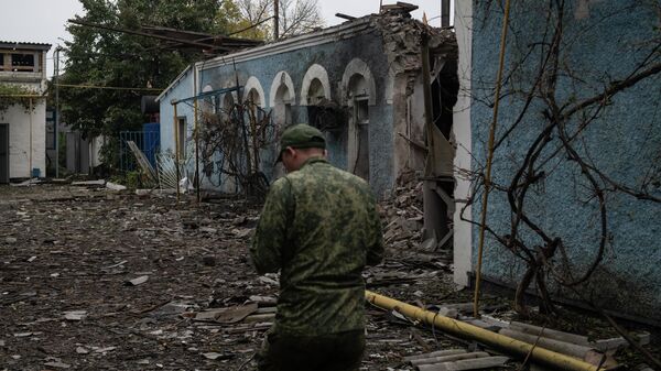 Мужчина на фоне разрушенного здания после обстрела со стороны ВСУ в городе Брянки в ЛНР