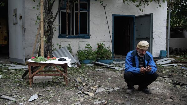 Мужчина на фоне поврежденного здания после обстрела со стороны ВСУ в городе Брянки в ЛНР