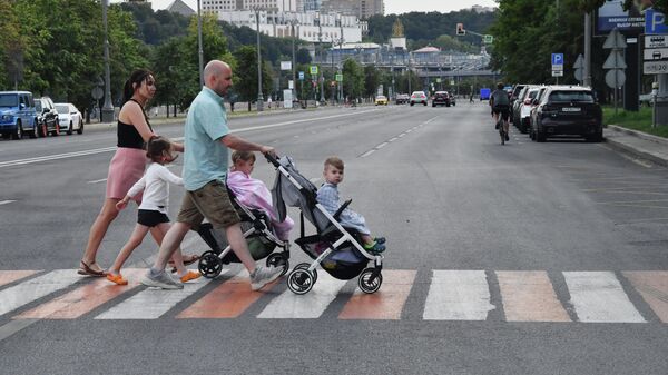 Семья с детьми переходит улицу по пешеходному переходу