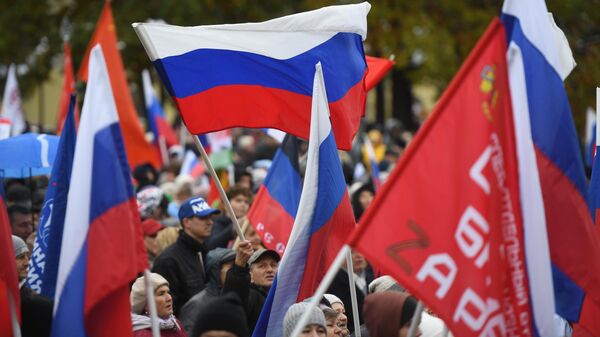 Люди с флагами во время митинга-концерта в честь присоединения ЛНР, ДНР, Херсонской и Запорожской областей к России в Центральном парке Новосибирска