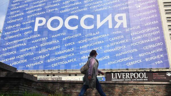 Женщина идет мимо здания с баннером Россия