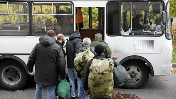Мужчины, призванные на военную службу в ходе частичной мобилизации, садятся в автобус на территории временного пункта мобилизации в павильоне №46 на ВДНХ в Москве