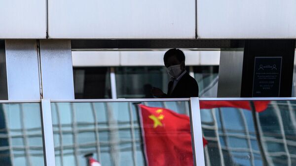 Мужчина проходит мимо отражения флага Китая на пешеходном мосту в Гонконге