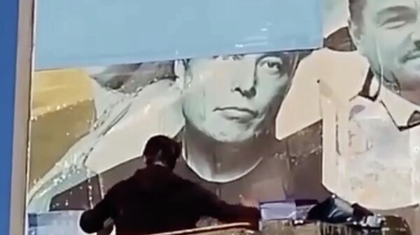 Рабочий заклеивает портрет Илона Маска на билборде в Одессе, Украина