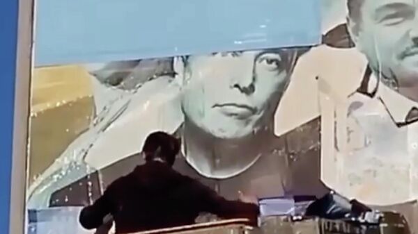 Рабочий заклеивает портрет Илона Маска на билборде в Одессе, Украина