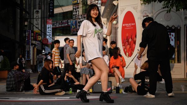 Девушка танцует на улице в районе Синчон в Сеуле