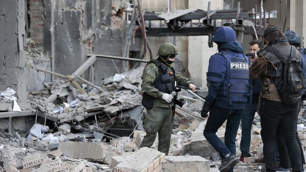 Следователь СК РФ и журналисты на месте пострадавшего в результате обстрела со стороны ВСУ здания городской администрации в центре Донецка