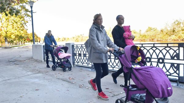 Родители с маленькими детьми гуляют по набережной в городе Энергодар