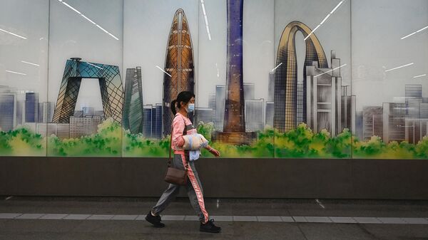 Женщина проходит мимо изображения центрального делового района Пекина