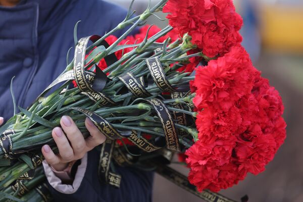 Цветы с траурной лентой во время похорон погибших при крушении самолета на новом кладбище города Ейск