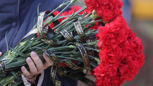 Цветы с траурной лентой во время похорон погибших при крушении самолета на новом кладбище города Ейск