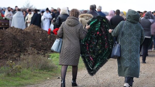 Горожане несут траурный венок во время похорон погибших при крушении самолета на новом кладбище города Ейск