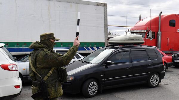 Сотрудник военной полиции регулирует движение в очереди на переправу во время эвакуации из Херсона
