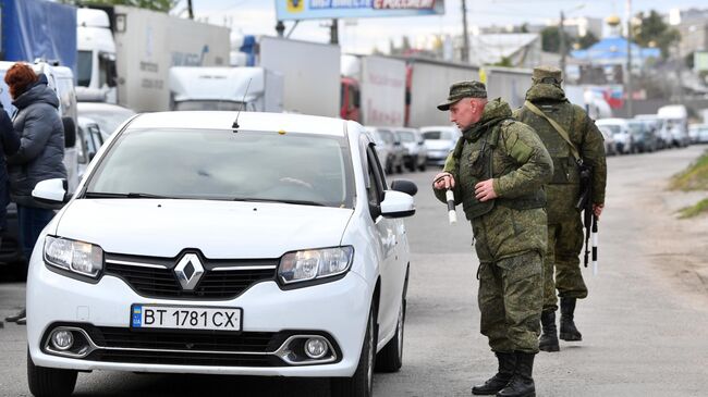 Сотрудники военной полиции регулируют движение в очереди на переправу в Херсоне