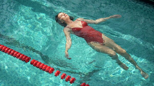 Девушка расслабляется после тренировки в бассейне 