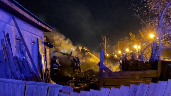 Сотрудники МЧС РФ тушат пожар в частном доме, возникший в результате падения самолета Су-30 в Иркутске