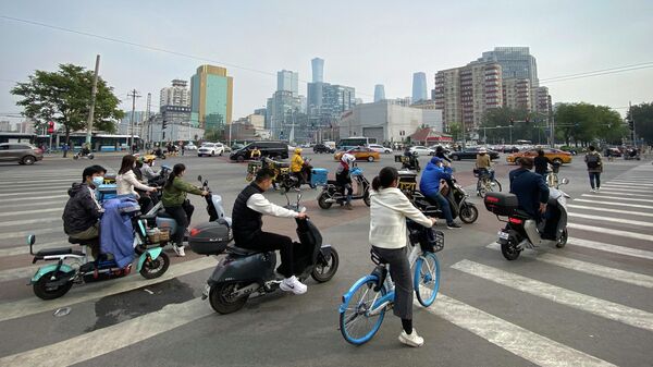 Люди на скутерах и велосипедах в центральном деловом районе Пекина