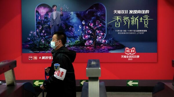 Сотрудник службы безопасности на фоне рекламного шита ко Дню холостяка на станции метро в Пекине