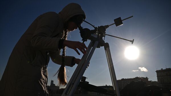 Девушка наблюдает в телескоп частичное солнечное затмение в Москве