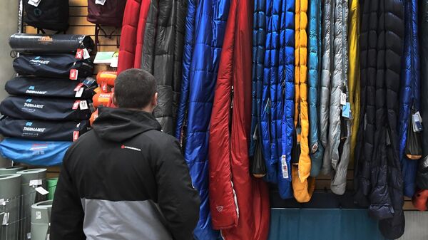 Покупатель выбирает спальный мешок в магазине товаров для туристов