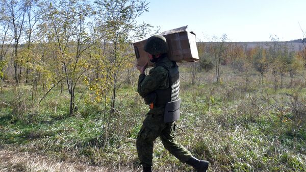 Мобилизованный военнослужащий РФ несет коробку с гумпомощью