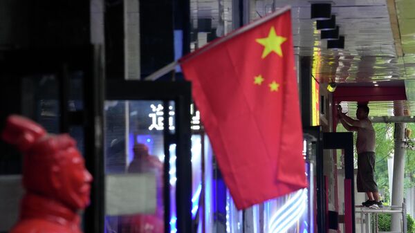 Рабочий возле национального флага в Китае