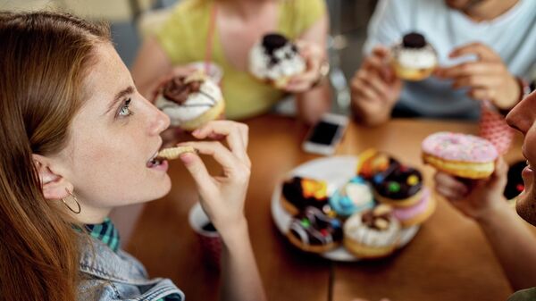 Девушка ест пончики с друзьями в кафе
