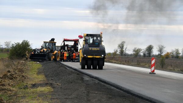 Сотрудники дорожно-строительной компании ремонтируют дорожное полотно в Запорожской области