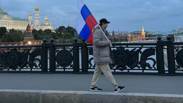 Мужчина с флагом России идет по Большому Каменному мосту после окончания митинга Своих не бросаем на Манежной площади в Москве.