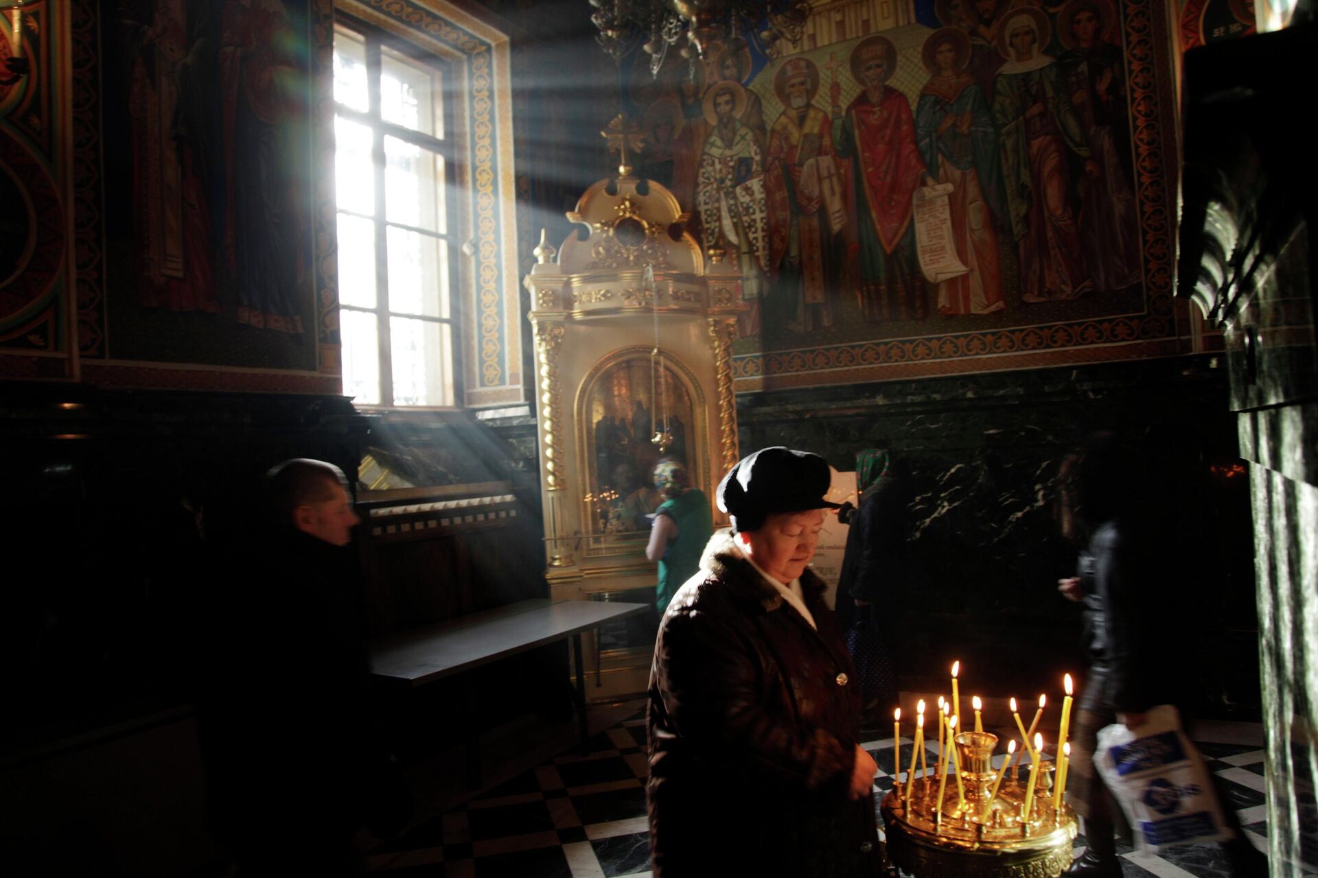 Женщина ставит свечу в православном храме в Кишиневе  - РИА Новости, 1920, 26.10.2023