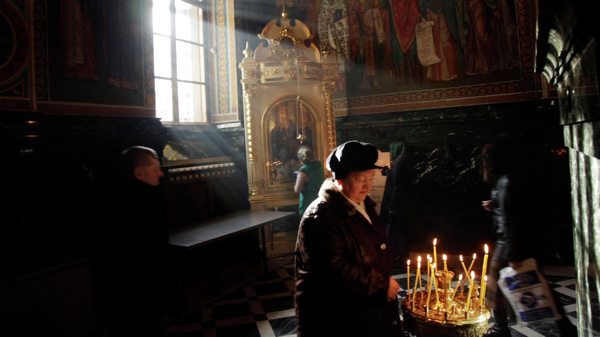 Женщина ставит свечу в православном храме в Кишиневе  - РИА Новости, 1920, 21.11.2023