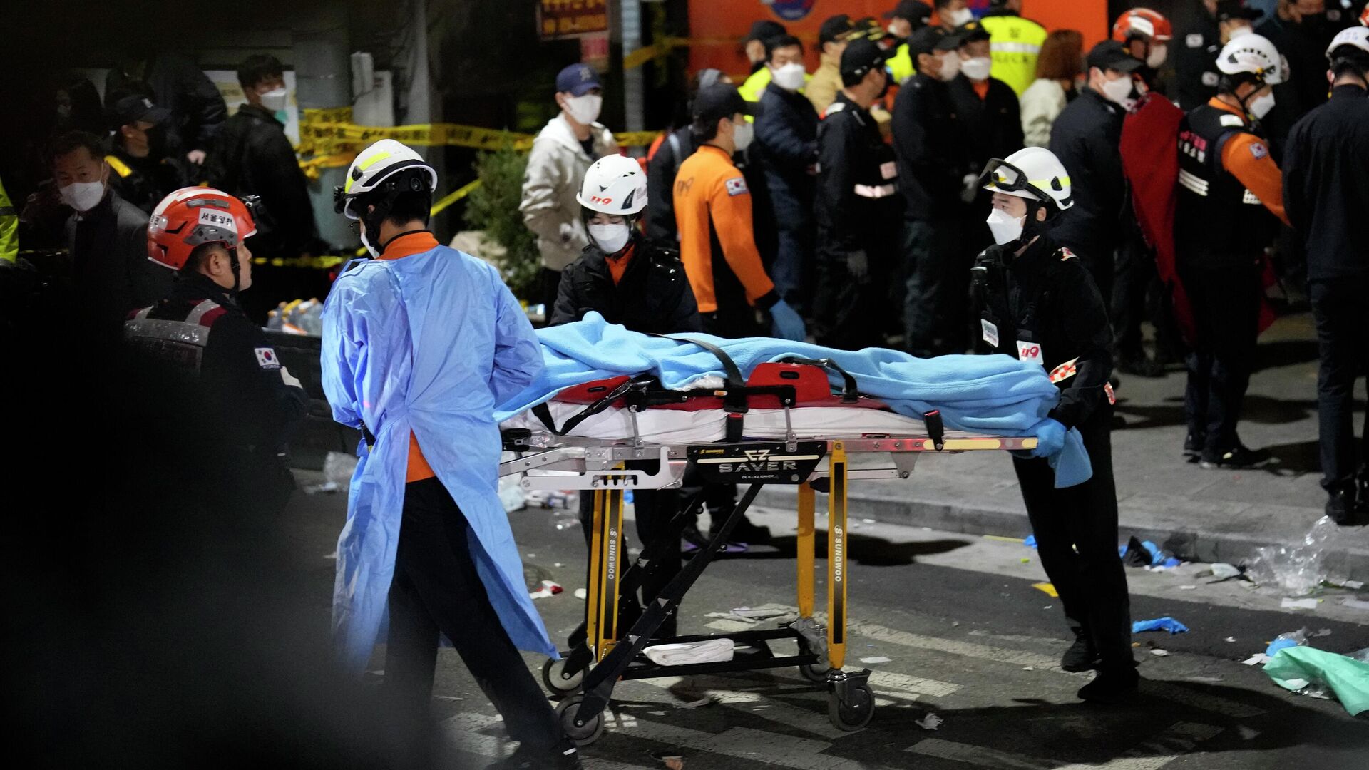 Спасатели несут пострадавшего на улице рядом с местом происшествия в Сеуле, где произошла давка - РИА Новости, 1920, 07.11.2022