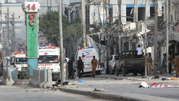 Сотрудники службы безопасности и машины скорой помощи на месте взрывов возле здания министерства образования в Могадишо