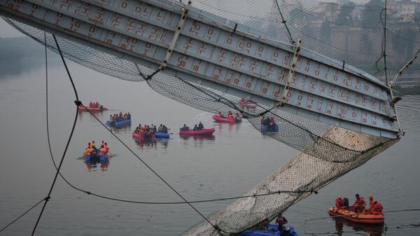 Спасатели ведут поиски рядом с местом обрушения подвесного вантового моста на реке Макчу город Морби, Гуджарат Индия