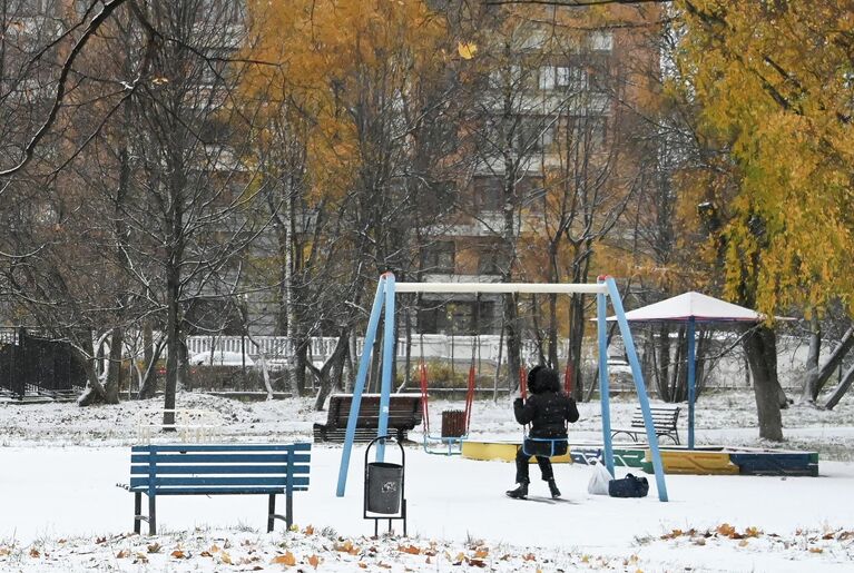 Девочка качается на качелях в заснеженном сквере на Ленинском проспекте в Москве