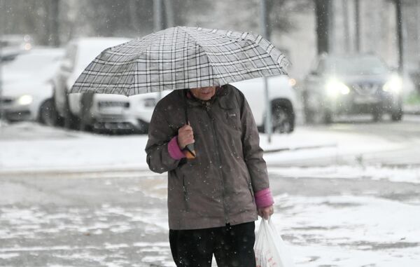 Женщина с зонтом идёт по Ленинскому проспекту во время снегопада в Москве