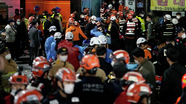 Спасатели пытаются вынести пострадавших с места трагедии в Сеуле, Южная Корея.